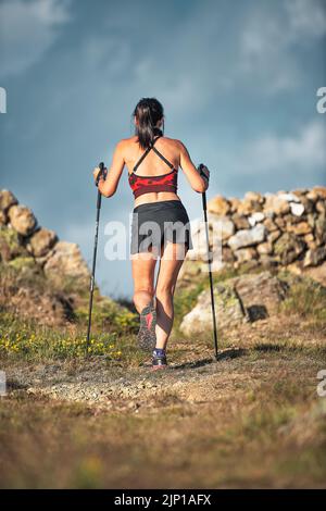 Sportliche Frau mit schönen athletischen Körper mit Skistöcken während der Exkursion Stockfoto