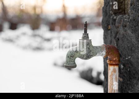 Alte rostige Retro-Gartenarmatur ohne Ventil draußen im verschneiten Garten Stockfoto