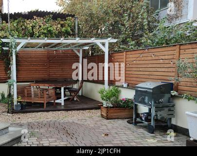 Pavillon mit Lichtern in der Nacht. Bild von einem Sommerhaus mit komfortablen Gartenmöbeln. Romantische Szene in der Dämmerung Stockfoto