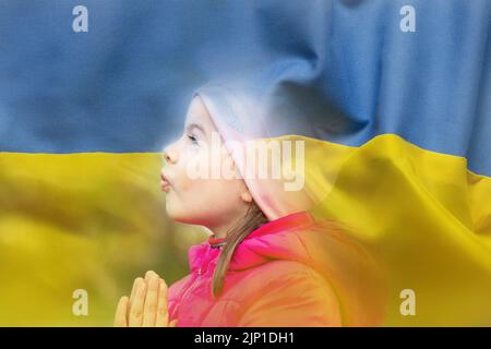 Ein Kind betet vor dem Hintergrund der Nationalflagge der Ukraine gelb-blaues Kindergebet für die Ukraine, bitte schließt den Himmel über der Ukraine 2022 Stockfoto