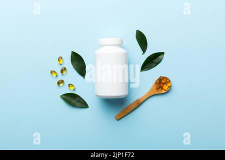 Omega-3 Kapseln liegen in einer weißen Flasche auf einem Tisch mit grünem Blatthintergrund. Fischöltabletten. Biologisch aktive Zusatzstoffe. omega 6, Omega 9, Vitam Stockfoto