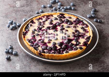 Köstliche Heidelbeertarte mit Vanillecreme und knuspriger Kruste in Nahaufnahme auf einem Teller auf dem Tisch. Horizontal Stockfoto