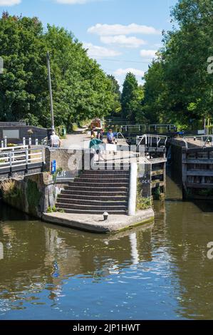 Junge Frau und zwei Jungen beobachten, wie ein Mann das Schleusentor für ein kleines Boot schließt, das durch Batchworth Lock, Rickmansworth, Hertfordshire, England, Großbritannien, fährt. Stockfoto