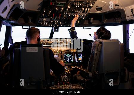 Kapitän und weibliche Copilot immer bereit, Flugzeug und Start mit Dashboard-Navigation im Cockpit Befehl fliegen. Airline-Crew zur Festlegung der Höhe und mit Bedienfeldtasten, fliegendes Flugzeug. Stockfoto