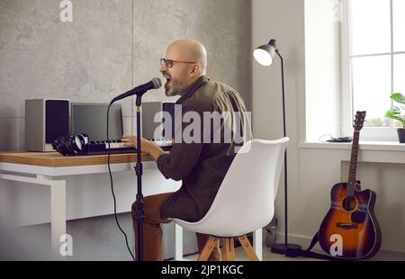 Kreativer Musiker, der in seinem Studio auf elektronischem Keyboard singt und Musik spielt Stockfoto