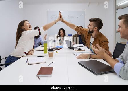 Glückliches Team, das Höchstfünf erreicht hat. Erfolg feiern mit Hi Five. Kollegen Freunde berühren Hände nach Abschluss der Arbeit perfekt. Stockfoto
