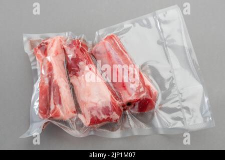 Schweineribs in vakuumverpackter Verpackung, versiegelt für das Sous-Vide-Kochen auf grauem Hintergrund in der Draufsicht. Stockfoto