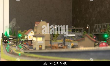 Miniatur des Bahnhofs. Modell der Lokomotive mit Dampf, der durch die Modellstation fährt. Miniatur der Stadt. Stockfoto