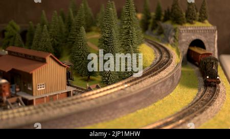 Modellzug, der aus dem Tunnel kommt. Elektrischer Modellzug auf Miniatur-Bahnstrecke durch Bergtunnel. Eisenbahnmodellierung. Stockfoto