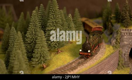 Modelleisenbahn und Modelleisenbahn aus nächster Nähe. Fahrgast Spielzeug Zug in Bewegung. Eisenbahnmodellierung. Stockfoto