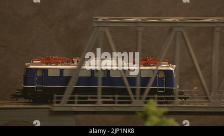 Miniatur-Dieselzug, der durch die Brücke fährt. Modell des alten Dieseltriebs in Bewegung. Stockfoto