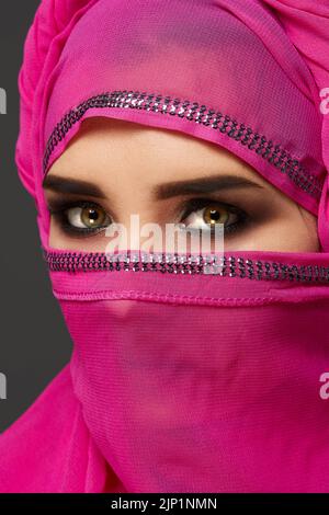 Nahaufnahme einer jungen, charmanten Frau, die den pinken Hijab trägt, der mit Pailletten verziert ist. Arabischer Stil. Stockfoto