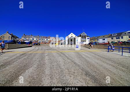 Newbiggin am Meer Northumberland schönes Küstendorf mit der RNLI-Station an der langen Promenade und Betonpiste gegen einen tiefblauen Summ Stockfoto