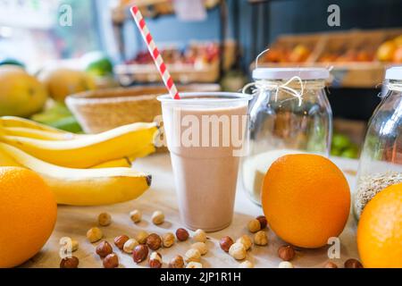 Gesunde Protein-Shake auf dem Tisch mit Obst und Gemüse Zutaten herum. Stockfoto