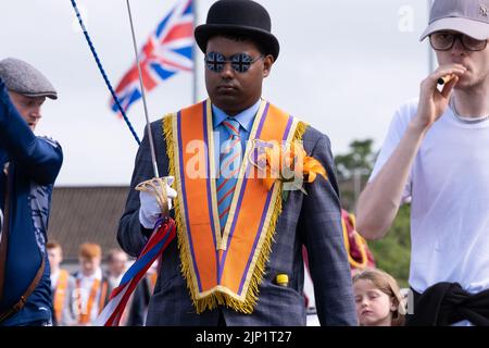 Ballymena, Großbritannien. 12. Juli 2022. Orange Order-Mitglied trägt Melone Hut und Union Jack Sonnenbrille trägt zeremonielle Schwert mit R dekoriert Stockfoto