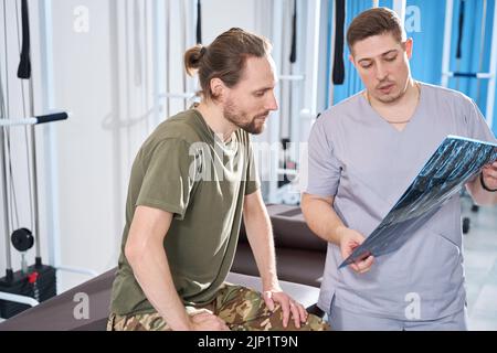 Der behandelnde Arzt kommuniziert mit dem Patienten im Rehabilitationszentrum Stockfoto