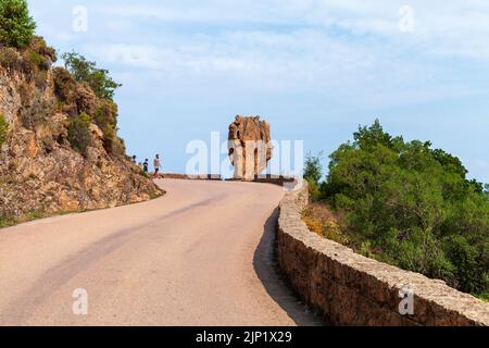 Korsika, Frankreich - 23. August 2018: Touristen laufen zu massiven Steinen, die auf einer Straße in Calanques de Piana stehen Stockfoto