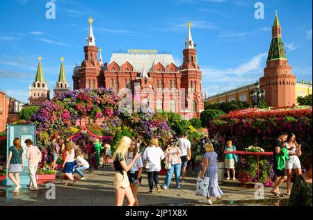 Blumenfest auf dem Manezhnaja-Platz, Moskau, Russland. Historisches Museum und Kreml, Sehenswürdigkeiten in der Ferne. Menschen Stockfoto