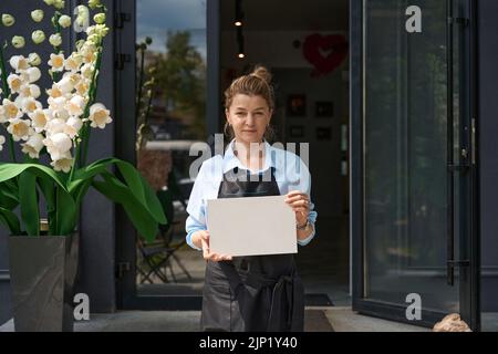 Portrait des Floristen, der vor der Blumenboutique draußen steht Stockfoto
