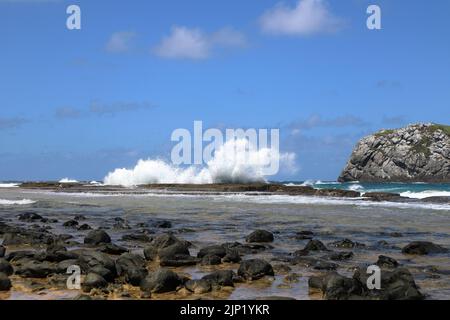 Starke Wellen treffen auf Felsen am Strand von Leao in Noronha, Praia do Leao. Stockfoto