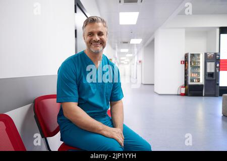 Arzt in blauer Ärztin lächelt lächelnd in der Krankenhauslobby Stockfoto