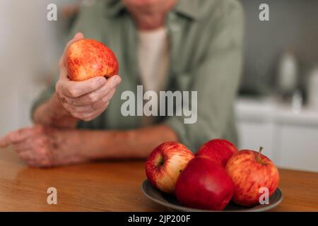 Nahaufnahme eines älteren Mannes, der Äpfel in seiner Küche hält. Stockfoto