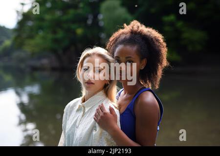 Junge Frauen verbringen Zeit zusammen in der Natur, in der Nähe des Sees, Konzept einer starken, lang anhaltenden Freundschaft. Stockfoto