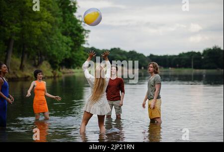 Multirassische Gruppe junger Freunde, die während des Sommers mit Ball im See spielen und Spaß haben. Stockfoto