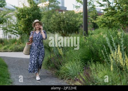 Reife Frau, die im Park spazieren geht und Zeit für sich selbst genießt. Stockfoto