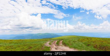 Wanderweg durch grasbewachsene Hügel. Bergkulisse im Sommer. cumulus Wolken am blauen Himmel über dem fernen Kamm. Entdecken sie ukrainische karpaten Stockfoto