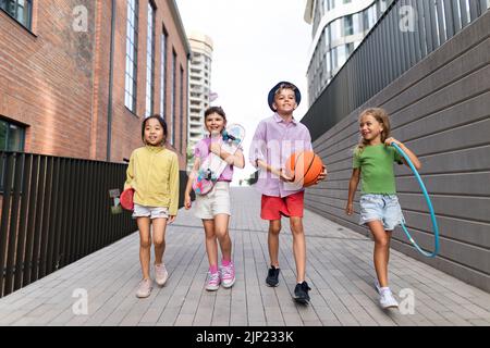 Fröhliche Kinder, die während des Sommers in der Stadt spielen und miteinander reden. Blick auf die Kamera, Low-Angle-Ansicht. Stockfoto