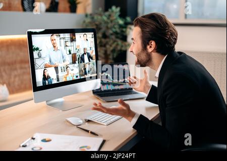 In seinem modernen Büro sitzt ein erfolgreicher kaukasischer männlicher Aktienmakler, spricht mit Kollegen auf einer Videokonferenz, erarbeitet eine Krypto-Strategie und diskutiert Risiken. Brainstorming der Gruppe durch Videoanruf Stockfoto