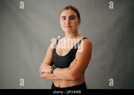 Fokussierte kaukasische Frau, die im Studio die Arme kreuzte Stockfoto