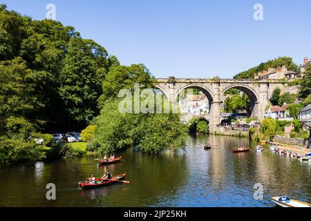 Der Eisenbahnviadukt über den Fluss Nidd, Knaresborough, North Yorkshire, England. Heißer Sommertag mit Menschen auf Booten im Fluss. Stockfoto