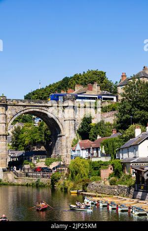 Der Eisenbahnviadukt über den Fluss Nidd, Knaresborough, North Yorkshire, England. Heißer Sommertag mit Menschen auf Booten im Fluss. Stockfoto