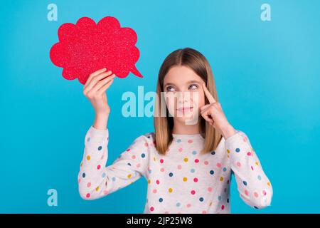 Foto von zweifelhaft unsicher kleine Mädchen tragen gepunktete Hemd Finger Kopf Tempel suchen leeren Raum isoliert blaue Farbe Hintergrund Stockfoto