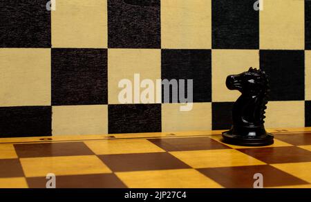 Schwarzer Ritter allein auf einem Schachbrett. Konzept von Leidenschaft, Führung, Verteidigung, Wettbewerb, Einfluss. Schachbrett aus Holz. Armee von einem. Stockfoto
