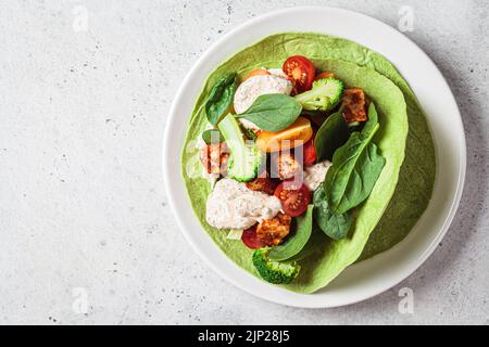 Offener veganer grüner Tortilla-Wrap mit Brokkoli, Tofu und Tomaten, Draufsicht. Vegetarisches Rezept, Comfort Food, pflanzliches Konzept. Stockfoto