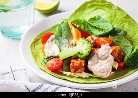 Offener veganer grüner Tortilla-Wrap mit Brokkoli, Tofu und Tomaten. Vegetarisches Rezept, Comfort Food, pflanzliches Konzept. Stockfoto