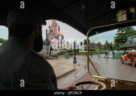 Ein erwachsener Mann, der in Disneyland mit dem Blick auf das 30.-jährige Schloss vor ihm fährt Stockfoto