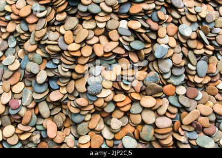 Muster aus glatten, abgerundeten Flusssteinen. Hintergrund von glatten Steinen in sanften Farben Stockfoto