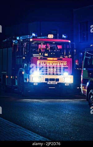 Eine vertikale Aufnahme eines roten deutschen Feuerwehrwagens im Nachtbetrieb Stockfoto