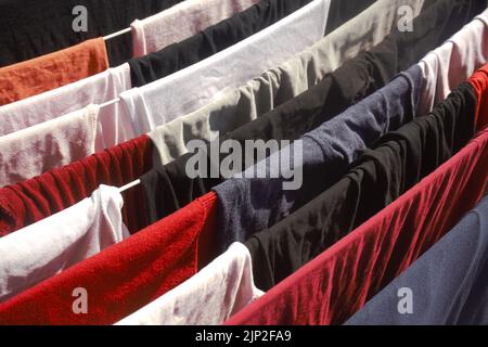 Eine Nahaufnahme von farbenfroher Wäsche, die an Seilen dicht beieinander hängt Stockfoto