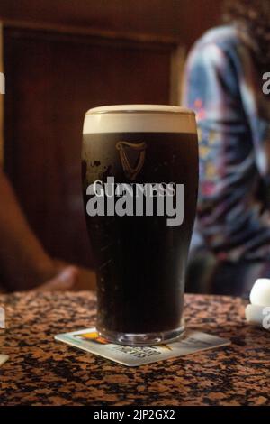 Eine vertikale Aufnahme eines Glases trockenem Guinness auf einem Marmortisch im Stags Head Pub, Irland Stockfoto