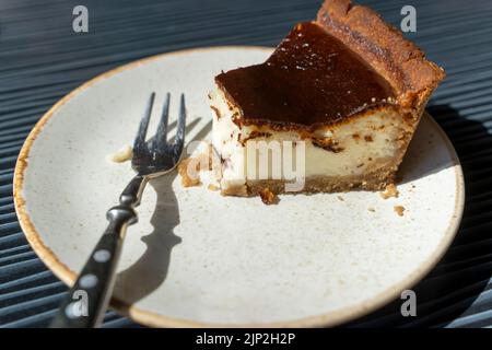 Ein halbgessene Käsekuchen auf einem Teller in einem Café und einer Gabel. Frühstück Stockfoto