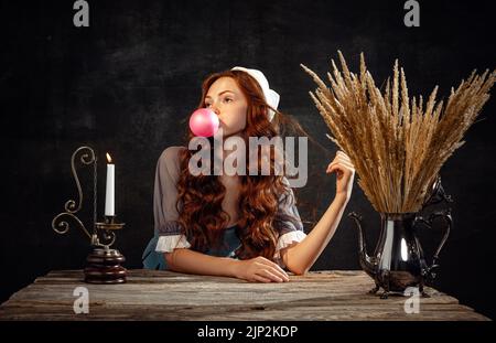 Vintage-Style. Junge charmante Rothaarmädchen mit langen lockigen Haaren wie Mädchen der Renaissance-Ära auf dunklem Hintergrund isoliert. Stockfoto