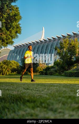 Hispanischer gutaussehender Mann beim Joggen während des Sonnenuntergangs im Parkgarten der Stadt der Künste und Wissenschaften, Valencia, Spanien. Stockfoto