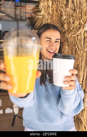 Eine junge Frau in einem Café mit einer Tasse Kaffee und einem Glas Saft. Stockfoto