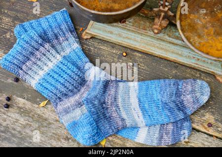 Ein Paar Stricksocken in Blautönen auf der Holzoberfläche Stockfoto