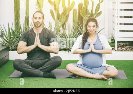 Schwangeren Mutter mit Ehemann Praxis Meditation Yoga für Ruhe und Entspannung gut für die Gesundheit des Babys Stockfoto